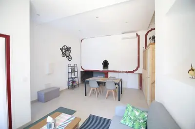a living room with a table and a white wall at T3 de 70m2 avec sauna, piscine intérieure chauffée in Siran
