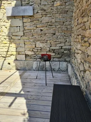 a chair sitting in front of a stone wall at T3 de 70m2 avec sauna, piscine intérieure chauffée in Siran