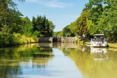 a boat on a river with trees and a bridge at T3 de 70m2 avec sauna, piscine intérieure chauffée in Siran