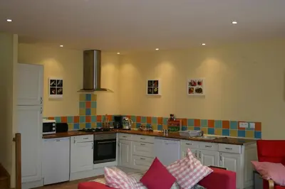 a kitchen with white cabinets and colorful tiles on the wall at Argein in Villautou