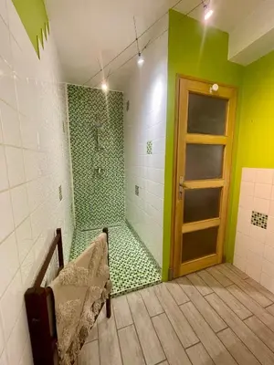 a bathroom with a shower with green and white tiles at Charmante maison de village in Pennautier