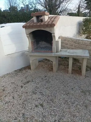 a outdoor pizza oven sitting next to a bench at Chez Sabine La campagne BIS in Narbonne