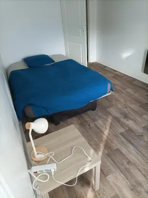 a bedroom with a bed and a table with a lamp at Chez Sabine La campagne BIS in Narbonne