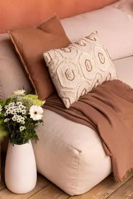 a couch with a pillow and a vase of flowers at Maison Zellige - Rooftop - Gruissan Center in Gruissan