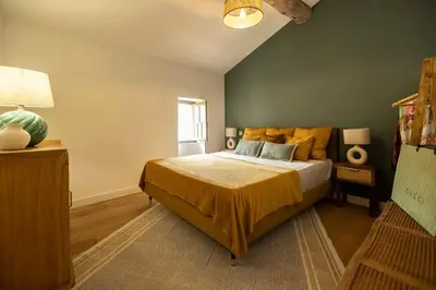 a bedroom with a bed with yellow sheets and a green wall at Maison Zellige - Rooftop - Gruissan Center in Gruissan