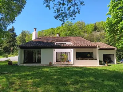 a small white house with a green yard at Maison de campagne avec lac privé in Fendeille