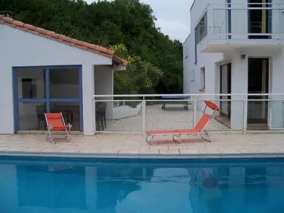 a swimming pool with two chairs and a house at Maison de campagne avec lac privé in Fendeille