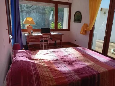 a bedroom with a bed and a desk with a laptop at Maison de campagne avec lac privé in Fendeille