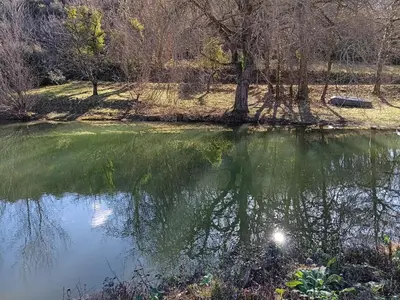 a body of water with trees in the background at Maison de campagne avec lac privé in Fendeille