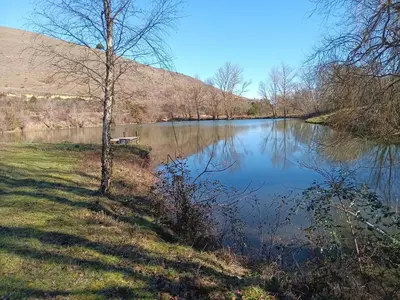 a view of a river with a bench next to it at Maison de campagne avec lac privé in Fendeille