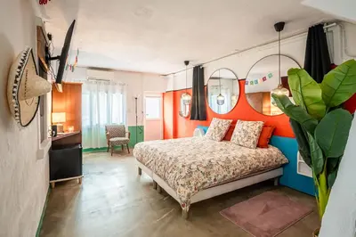 a bedroom with a large bed and a kitchen at Casa Amor Balnéo Sauna in Lézignan-Corbières