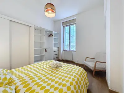 a bedroom with a yellow and white bed and a window at Le Petit Sud - Appartement Proche des Halles - Wifi in Narbonne