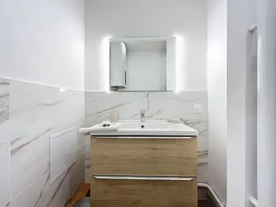 a white bathroom with a sink and a mirror at Le Petit Sud - Appartement Proche des Halles - Wifi in Narbonne