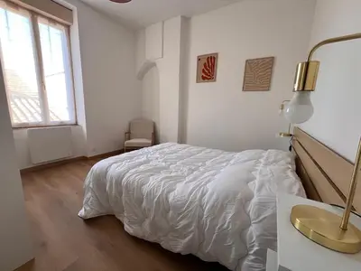 a white bedroom with a bed and a desk and a window at Le Petit Sud - Appartement Proche des Halles - Wifi in Narbonne