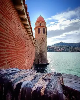 a brick wall with a tower next to a body of water at Vue D Ansignan in Ansignan