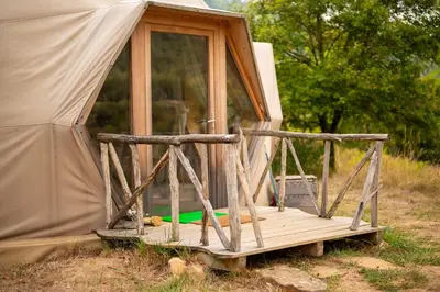 a small tent with a wooden porch in a field at Centre Harmonia in Rennes-les-Bains