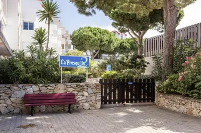 a park bench with a blue street sign next to a fence at Appartement Studio Cabine - proche plage du Grazel GN400-032 in Gruissan