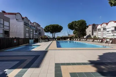 a swimming pool with chairs and trees and buildings at Appartement Studio Cabine - proche plage du Grazel GN400-032 in Gruissan