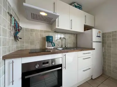 a kitchen with white cabinets and a sink and a stove at Appartement Studio Cabine - proche plage du Grazel GN400-032 in Gruissan
