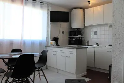 a kitchen with white cabinets and a table with chairs at Appartement Studio PORT LA NOUVELLE PN480-074 in Port-la-Nouvelle