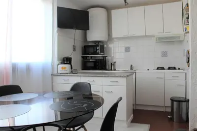 a kitchen with two tables and a kitchen with white cabinets at Appartement Studio PORT LA NOUVELLE PN480-074 in Port-la-Nouvelle