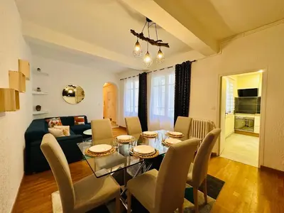 a dining room and living room with a table and chairs at La Citadine in Carcassonne
