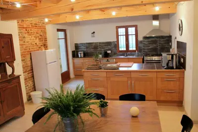 a large kitchen with wooden cabinets and a table at La Ferme de Bellune in Mazères