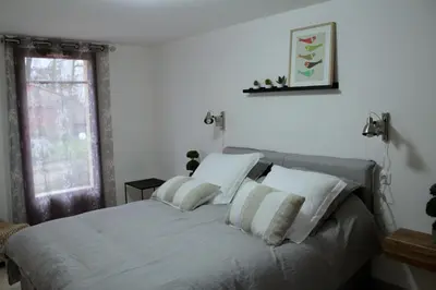 a bedroom with a bed with white sheets and a window at La Ferme de Bellune in Mazères