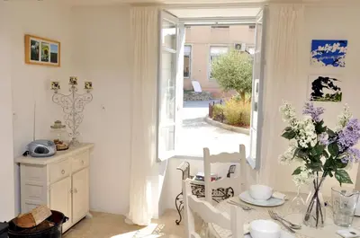 a white dining room with a table and a window at Chez LuLu Holiday Home in Olonzac