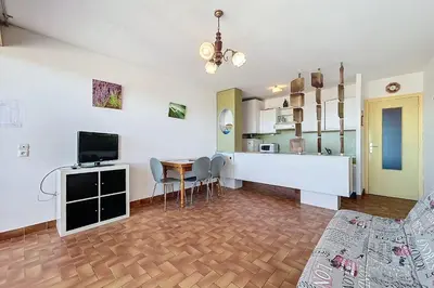 a living room with a kitchen and a dining room at Charming T2 with terrace on the seafront in Port-la-Nouvelle