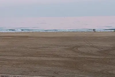 an empty beach with a person standing on the sand at Charming T2 with terrace on the seafront in Port-la-Nouvelle