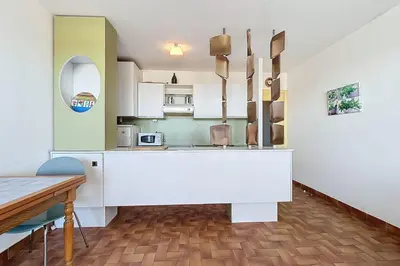 a kitchen with a white counter and a table at Charming T2 with terrace on the seafront in Port-la-Nouvelle