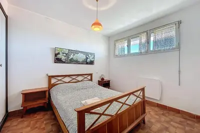 a bedroom with a bed and two windows at Charming T2 with terrace on the seafront in Port-la-Nouvelle