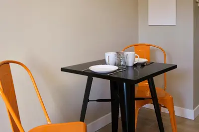 a table with two chairs and a black table with plates and cups at Au Céladon Parking gratuit, WIFI, Terrasse, Piscine in Carcassonne