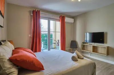 a bedroom with a bed with red curtains and a tv at Au Céladon Parking gratuit, WIFI, Terrasse, Piscine in Carcassonne