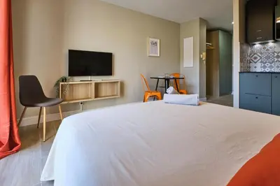 a bedroom with a white bed and a flat screen tv at Au Céladon Parking gratuit, WIFI, Terrasse, Piscine in Carcassonne