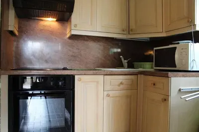 a kitchen with wooden cabinets and a black oven at Maison 3 pièces 6 couchages PORT LA NOUVELLE PN340-040 in Port-la-Nouvelle