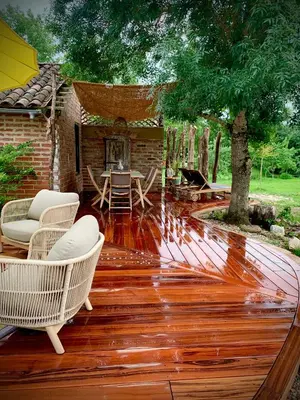 a deck with chairs and a table and a tree at La Main du Cœur Chambre d'hôtes de charme à la campagne in Loubens-Lauragais