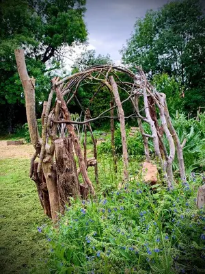 a structure made out of tree branches in a garden at La Main du Cœur Chambre d'hôtes de charme à la campagne in Loubens-Lauragais