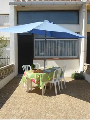 a table and chairs under a blue umbrella at Bright Family Home Near the Sea in Port-la-Nouvelle