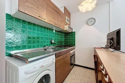 a kitchen with a washing machine and a clock on the wall at Bright Family Home Near the Sea in Port-la-Nouvelle