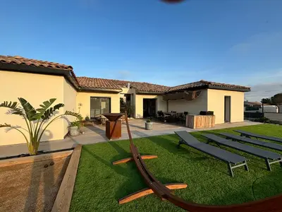 a house with a yard with a hammock in the grass at Villa paisible au bord des vignes in Sallèles-dʼAude