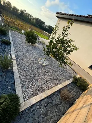 a rock garden with a tree and a building at Villa paisible au bord des vignes in Sallèles-dʼAude