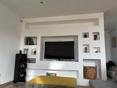 a living room with a flat screen tv on a white wall at Villa paisible au bord des vignes in Sallèles-dʼAude