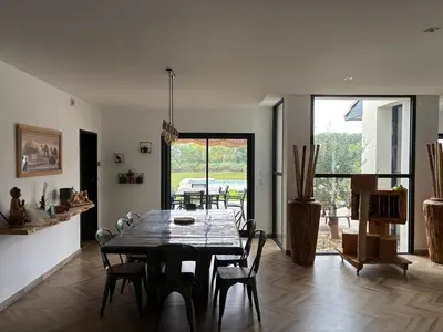 a dining room with a wooden table and chairs at Villa paisible au bord des vignes in Sallèles-dʼAude