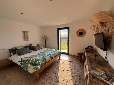 a bedroom with a bed and a tv and a window at Villa paisible au bord des vignes in Sallèles-dʼAude