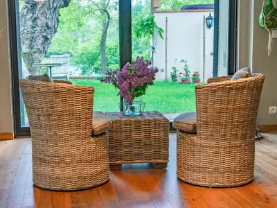 three wicker chairs and a table with a vase at Le COULOUMIER côté lac in Caignac