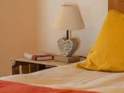 a bed with a table with a lamp on it at Le COULOUMIER côté lac in Caignac