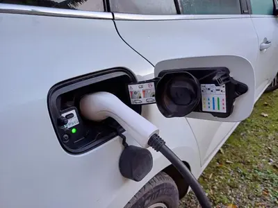 a charging station on the side of a white car at Le COULOUMIER côté lac in Caignac