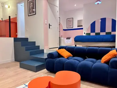 a living room with a blue couch and a staircase at Appartement Thème Années 60' l Baignoire Jets l Clim l Netflix in Castres